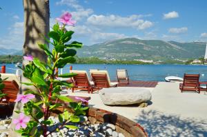 eine Gruppe von Stühlen auf einer Terrasse neben dem Wasser in der Unterkunft Apartments Dubravcevic in Tivat