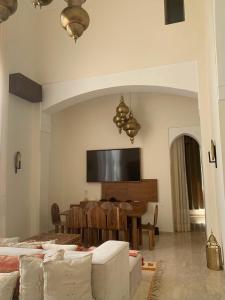 een woonkamer met een tafel en een televisie aan de muur bij Villa Magnolia - Amelkis Golf in Marrakesh