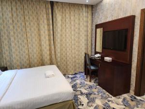 a hotel room with a bed and a desk and a television at EWG Al Hamra Hotel in Jeddah