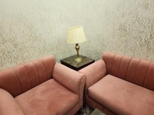 two brown leather couches sitting next to a table with a lamp at EWG Al Hamra Hotel in Jeddah