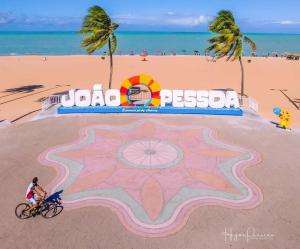 Chocolate com pimenta Edifício - Praia do Bessa في جواو بيسوا: شخص يركب دراجة على الشاطئ