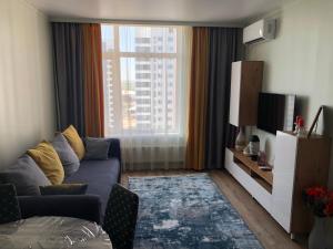 uma sala de estar com um sofá e uma grande janela em Esil Plaza Apartment em Astana