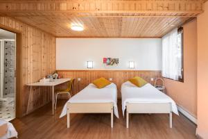 two beds in a room with a table at Motel-Restaurant 13 Etoiles in Sierre