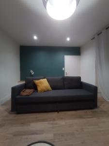 un sofá negro en una sala de estar con una pared azul en Le petit Beure en Beure