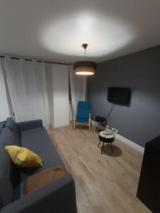 een woonkamer met een blauwe bank en een stoel bij Le petit Beure in Beure