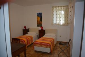 a room with two beds and a table and window at B&B La Casa Rossa in Paola