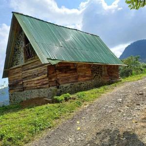 an old wooden barn with a green roof on a hill at Preciosa Cabaña alpina en zona rural in Dosquebradas