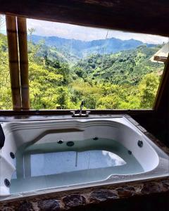 a bath tub in front of a window with a view at Preciosa Cabaña alpina en zona rural in Dosquebradas