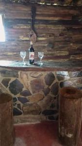 a bottle of wine and two glasses on a stone counter at Preciosa Cabaña alpina en zona rural in Dosquebradas