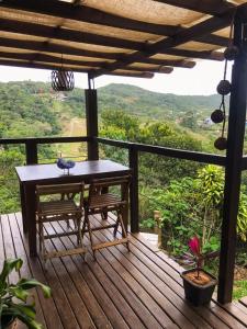 una terraza de madera con mesa y banco en Pescador de Sonhos en Praia do Rosa