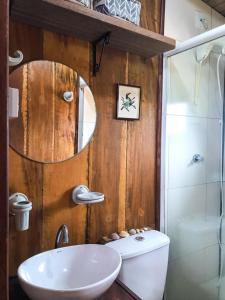 a bathroom with a sink and a toilet and a mirror at Pescador de Sonhos in Praia do Rosa