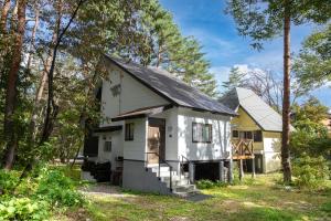 a white house in the woods with trees at Pension Eastmountain Hakuba in Hakuba