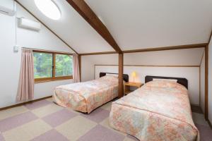 a bedroom with two beds and a window at Pension Eastmountain Hakuba in Hakuba