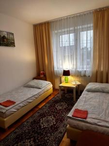 1 dormitorio con 2 camas y mesa con lámpara en Pokoje Gościnne Impresja Kadzidło, en Kadzidło