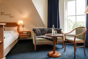 a hotel room with a bed and two chairs and a table at Sunderland Hotel in Sundern