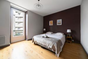 um quarto com uma cama grande e uma janela grande em Le Gramont - Grand appartement design, 3 chambres, Centre Ville em Vichy