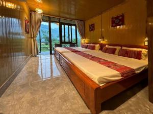a large bedroom with two beds and large windows at Nha Tan - Mai Chau Homestay and Tours in Mai Châu