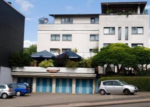 un edificio con coches estacionados en un estacionamiento en Hotel & Wirtshaus Hansen, en Bergisch Gladbach