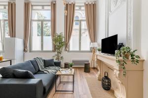 a living room with a blue couch and some windows at Charmant & spacieux appartement en cœur de ville in Saint-Étienne +7 photos