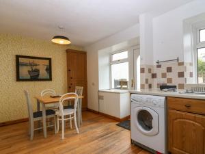 a kitchen with a table and a washing machine at 15 Main Street in Peterhead