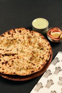 une pizza au fromage assise sur une table à côté d'une assiette dans l'établissement Hotel Olive New Delhi, à New Delhi