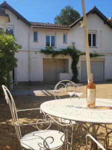 a table and chairs with a bottle of wine on it at Villa les Tilleuls - Arènes de Béziers in Béziers