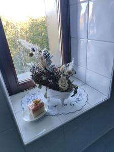 einen Tisch mit einem Kuchen und einem Blumenarrangement in einem Fenster in der Unterkunft Die Hube in Leutschach