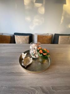 a table with a plate with a vase and flowers on it at Die huis 14-Een oase van rust tussen polders en kust in Ostend