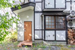 a house with a wooden door and a window at Pension Eastmountain Hakuba in Hakuba