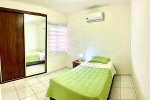 a bedroom with a green bed and a mirror at HERMOSA Y COMODA CASA " En condominio Privado " in Santa Cruz de la Sierra