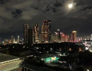 a city skyline at night with the moon in the sky at Condo with Balcony at Makati SM Jazz in Manila