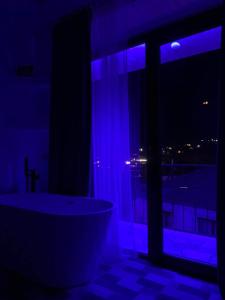 a bathroom with a tub and a window with blue lights at Sunny guesthouse in Kazbegi