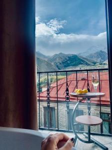 vistas a un balcón con una mesa y copas de vino en Sunny guesthouse en Kazbegi