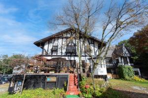 an old house with a large building at Pension Eastmountain Hakuba in Hakuba