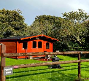 una cabaña naranja con una valla delante en Primrose Cabin, en Dorchester
