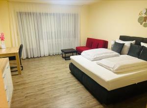 a hotel room with a bed and a red chair at Hotel & Restaurant Olio é Pane in Enzklösterle