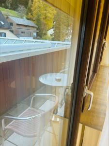 ein Glasfenster mit einem Stuhl und einem Tisch auf dem Balkon in der Unterkunft Hotel & Restaurant Olio é Pane in Enzklösterle