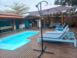 uma piscina com duas espreguiçadeiras e um guarda-sol em Pousada Inn Nature em Palhoça