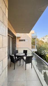 Abdoun Falls Luxury Apartment في عمّان: فناء مع كراسي وطاولة على شرفة