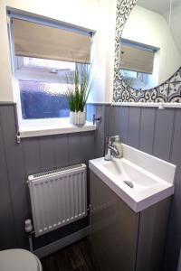 a bathroom with a sink and a mirror and a radiator at Fully renovated spacious home, Sleeps 5, in Grantham