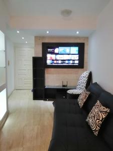 ein Wohnzimmer mit einem schwarzen Sofa und einem Flachbild-TV in der Unterkunft Apartamento Deluxe Isla Margarita - Costa Azul in Porlamar