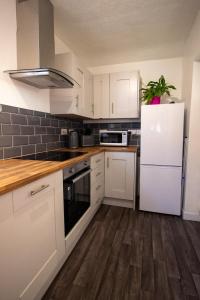cocina con armarios blancos y nevera blanca en Fully renovated spacious home, Sleeps 5,, en Grantham