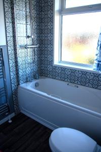 baño con bañera, aseo y ventana en Fully renovated spacious home, Sleeps 5, en Grantham