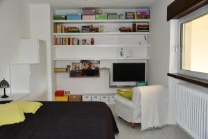 1 dormitorio con 1 cama, 1 silla y TV en Il giardino delle ortensie, en Vogogna