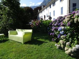 Una silla blanca sentada en la hierba junto a unas flores. en Il giardino delle ortensie, en Vogogna