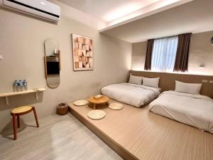 a small room with two beds and a table at 河趣泊旅 River Chill Inn in Tainan