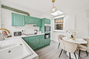 a kitchen with green cabinets and a table with chairs at Luxury 1 Bed Retreat With Free Parking - FREE NETFLIX & WIFI in Chatham