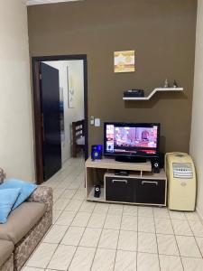 a living room with a tv and a couch at Casa em frente à praia Boracéia in Boracéia