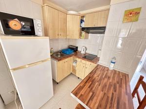 cocina pequeña con nevera blanca y suelo de madera en Apartments in Tenerife, en Playa de las Américas