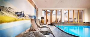 a large room with a swimming pool and a house at Hotel Elisabeth Superior Sölden in Sölden